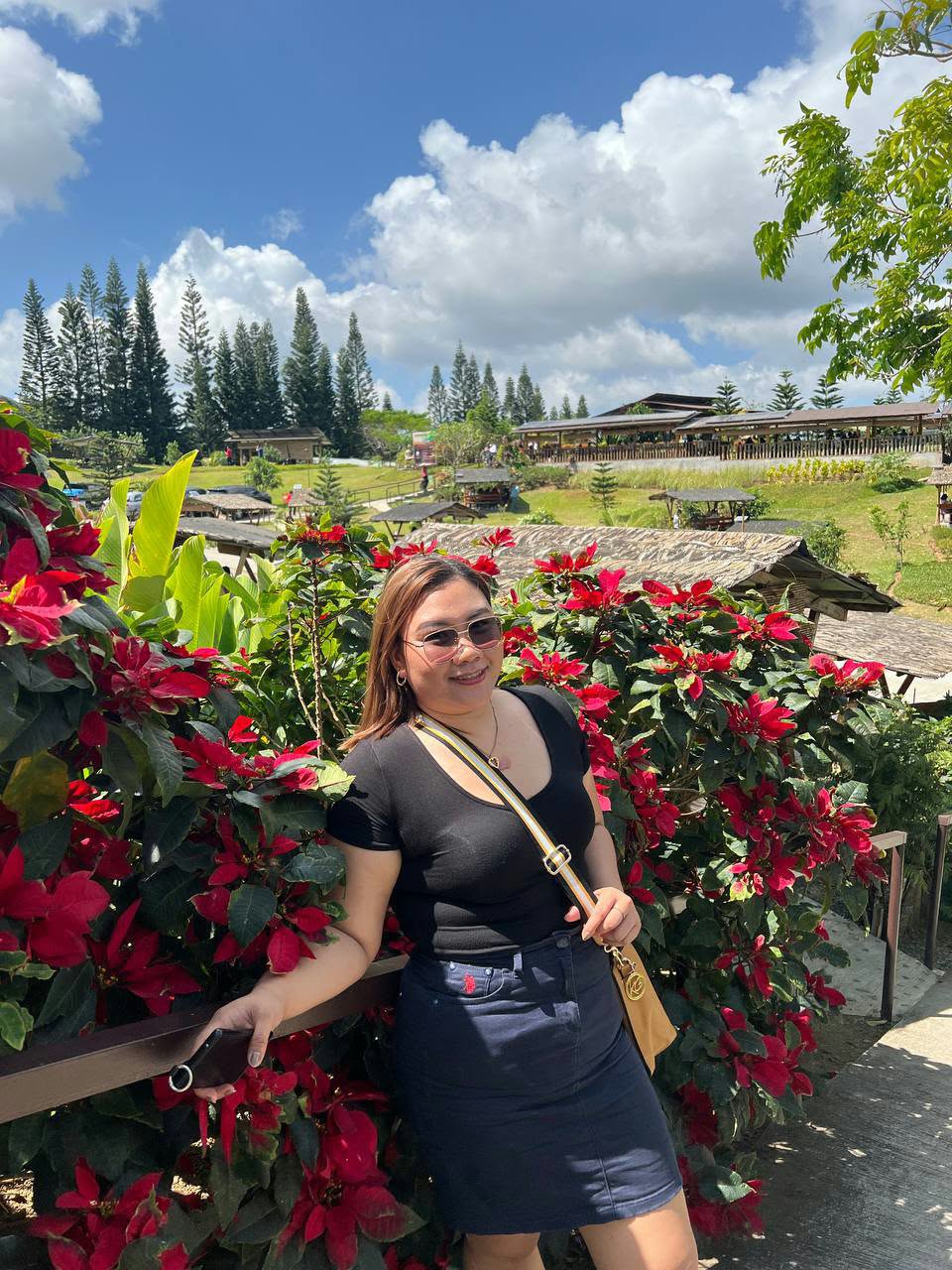 Ivy standing beside red flowers with a green landscape behind her